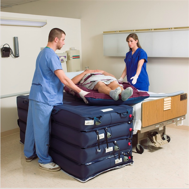Two healthcare workers lifting a patient using a specialized transfer device.