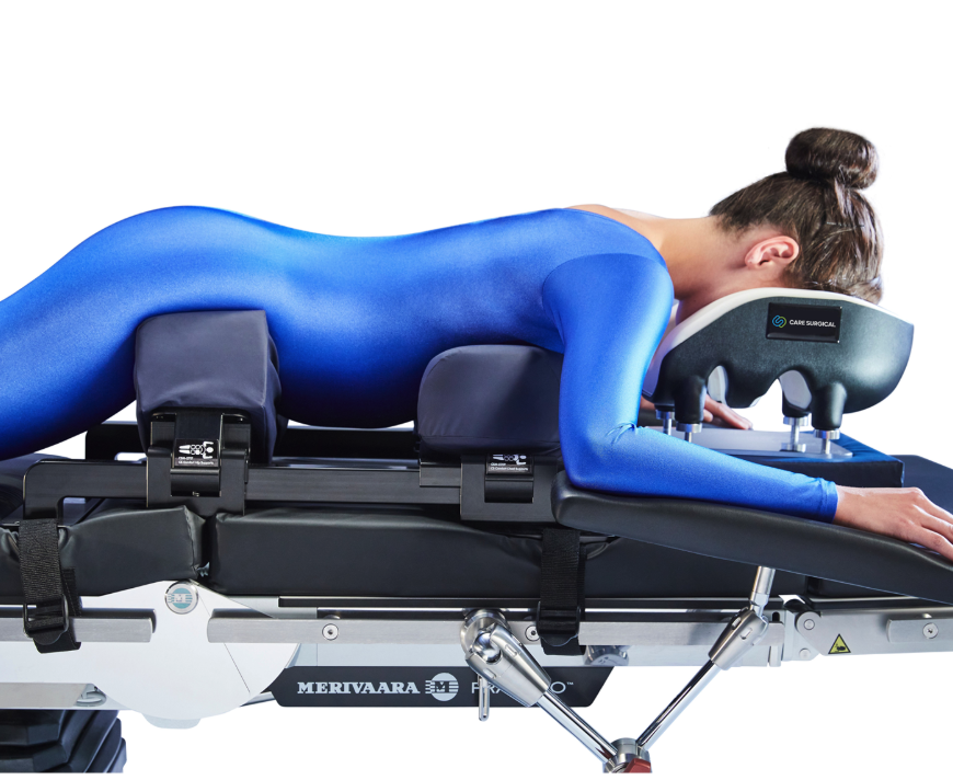 Person in blue bodysuit lying face down on a therapy or medical table.