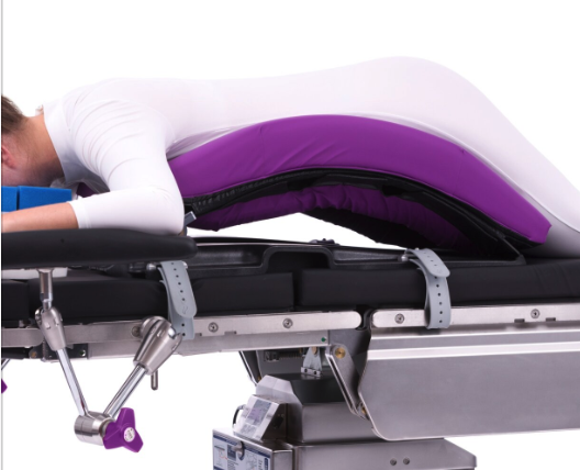 Person in white and purple attire lying on a medical table.