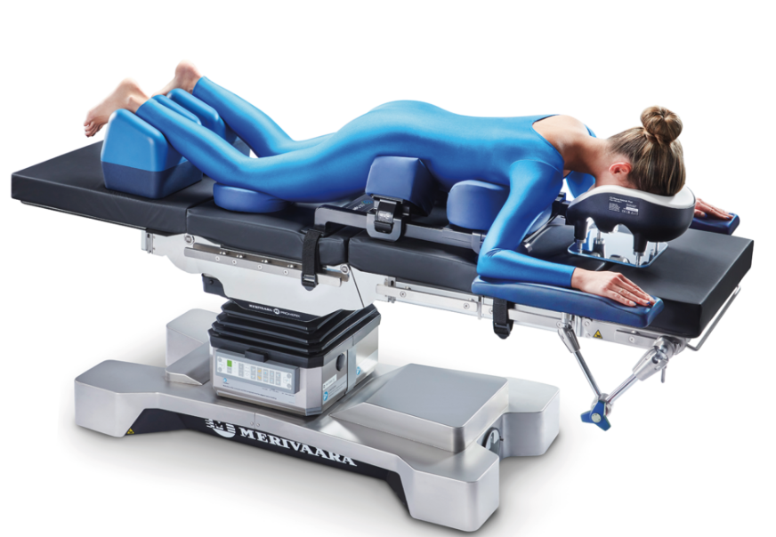 Person in blue suit receiving a therapy or treatment on a specialized medical table.