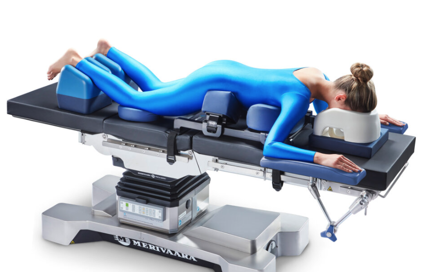 Two people in blue bodysuits lying on a medical table, engaging in therapy or treatment.