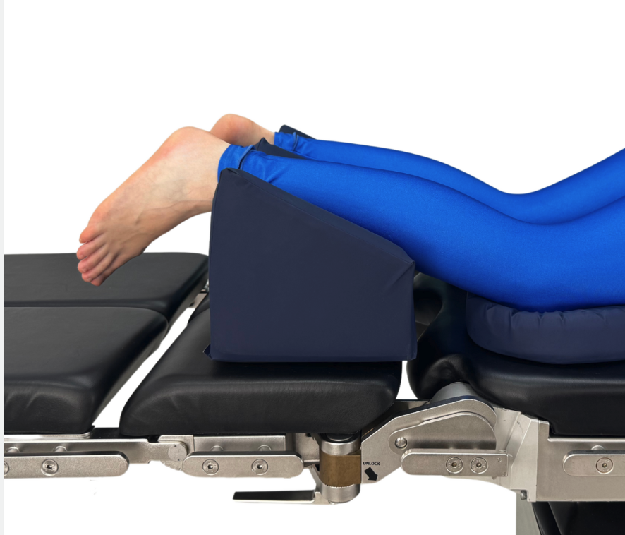 Blue leg wedge cushion elevating legs on medical table.