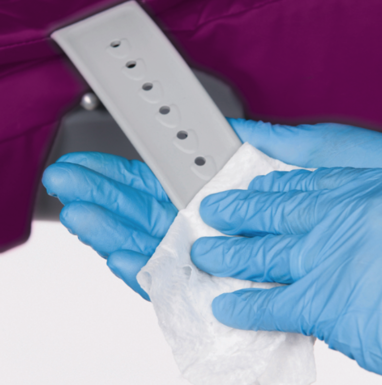 Person cleaning a white watch strap with a cloth while wearing blue gloves.