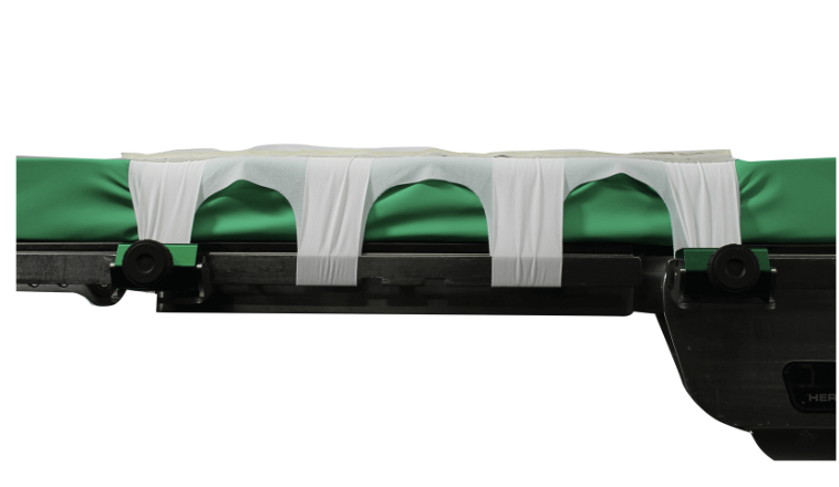 A green and white medical stretcher with straps.