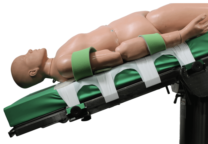 A medical training mannequin secured on a stretcher with green straps.