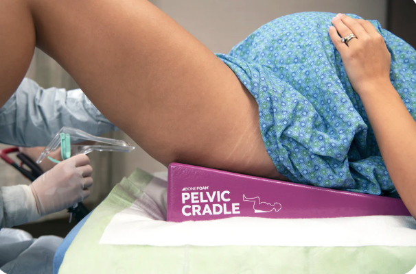 A person lying on a purple pelvic cradle during a medical procedure.