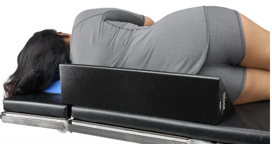 Person lying on a medical examination table in a gray shirt.