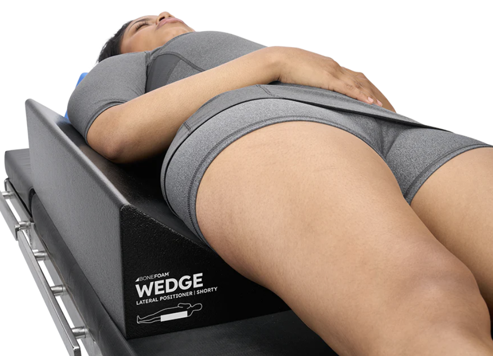 Person lying on a wedge cushion for support and comfort.