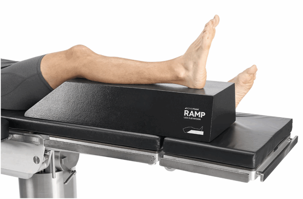 Leg positioned on a black orthopedic ramp support for therapy or examination.