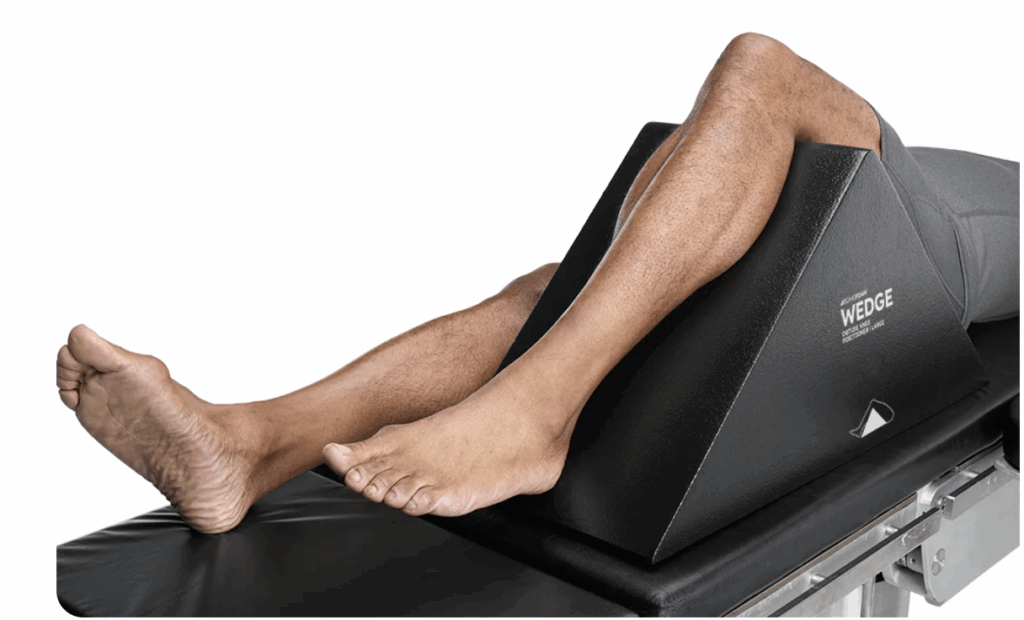 Person's legs resting on a black angled support cushion.