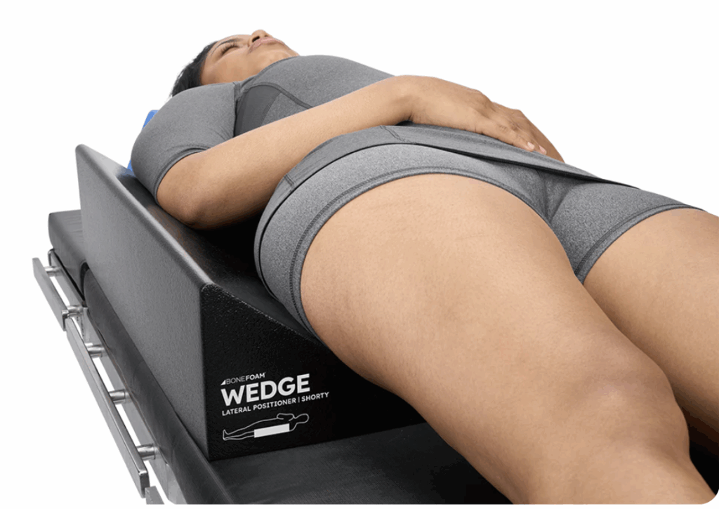 Person lying on a WEDGE back stretcher for posture support.