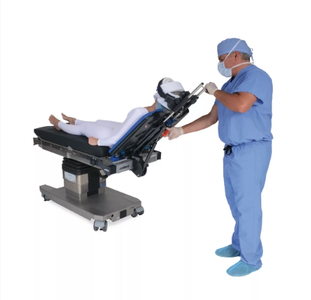 Medical professional adjusting operating table with patient ready for surgery.