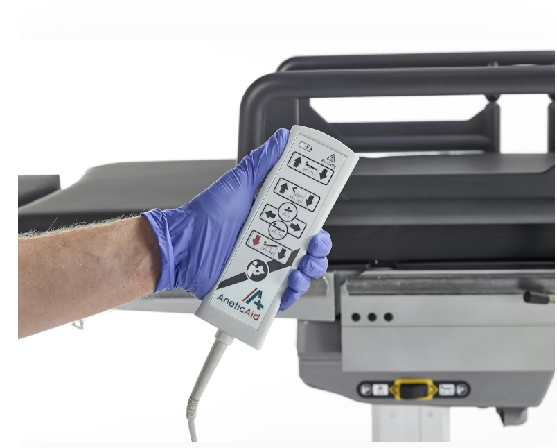 A gloved hand holding a remote control near a machine.